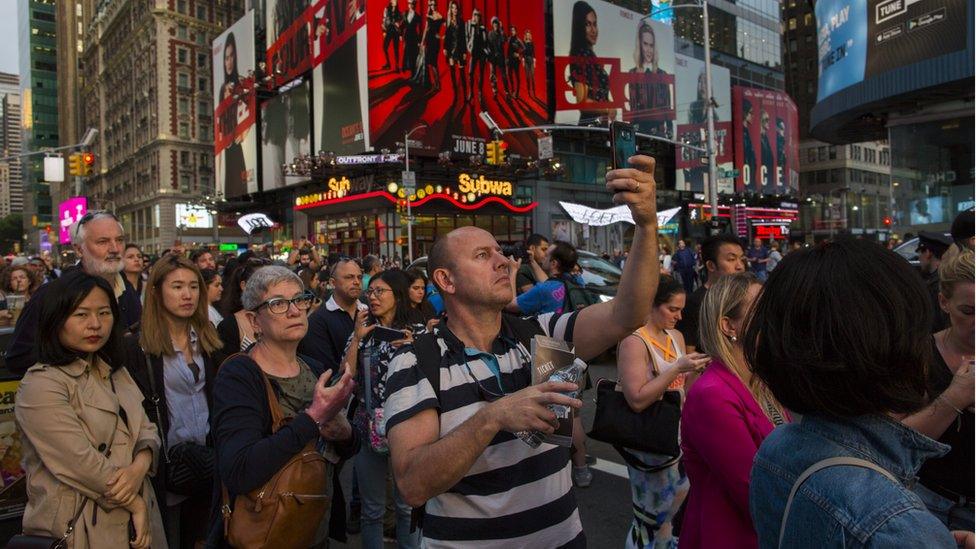 People take pictures of the phenomenon known as Manhattanhenge on Times Square