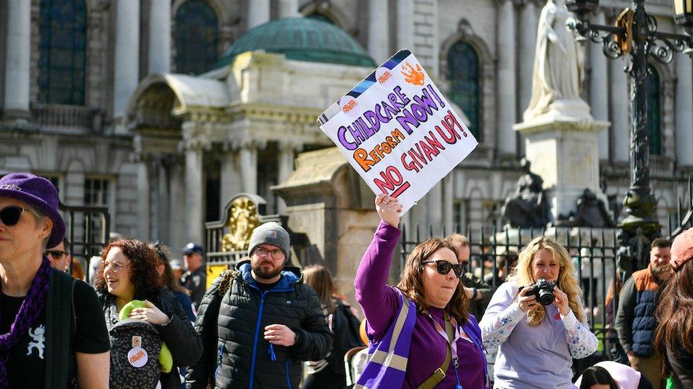 Woman holding a sign that reads 'childcare reform now! No Givan up!'