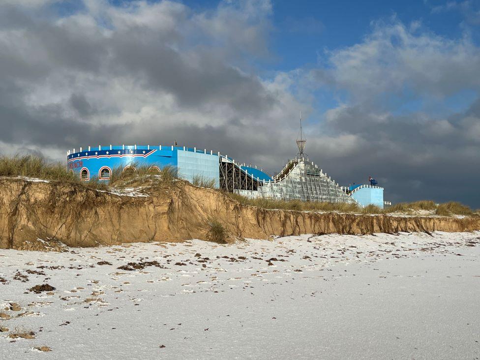 Grey clouds over the snow covered beach and rollercoaster