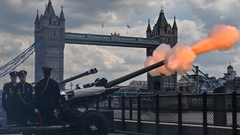 a canon fires bright orange across the river thames with tower bridge in the background