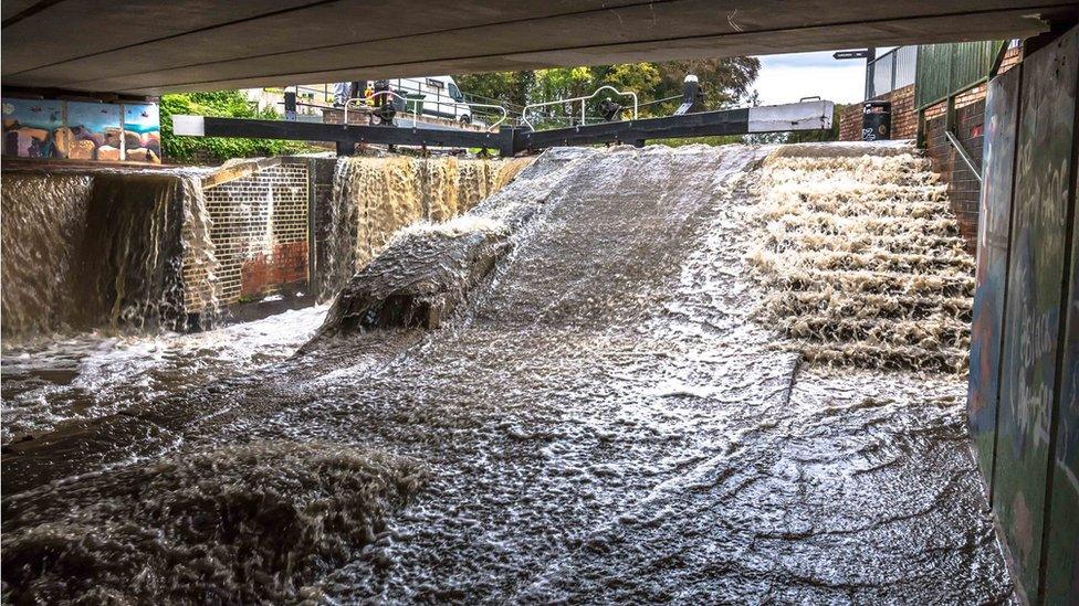 Canal overflowing from a lock onto a walkway in Dudbridge near Stroud