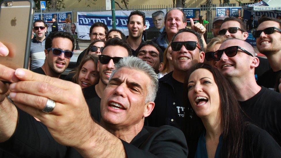 Israeli MP and chairperson of centre-right Yesh Atid party, Yair Lapid, takes a selfie with his wife Lihi (R) and his supporters, outside a polling station on 17 March 2015 in Tel Aviv