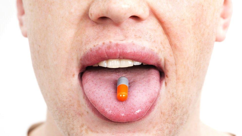 man with pill on his tongue