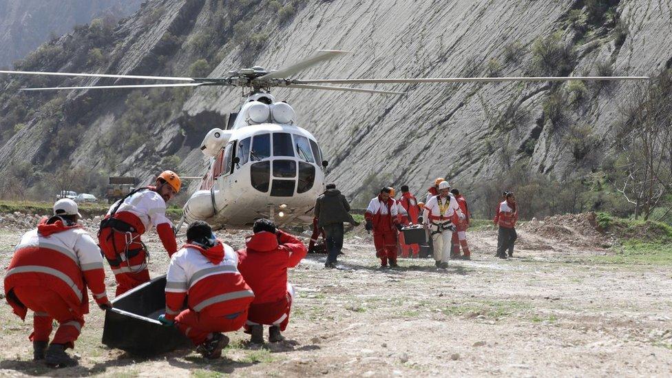 Iranian Red Crescent personnel carry the remains of people killed in a plane crash near Shahr-e Kord, in south-western Iran (12 March 2018)