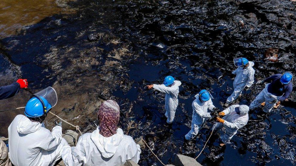 Workers clearing up an oil spill on a Peruvian beach