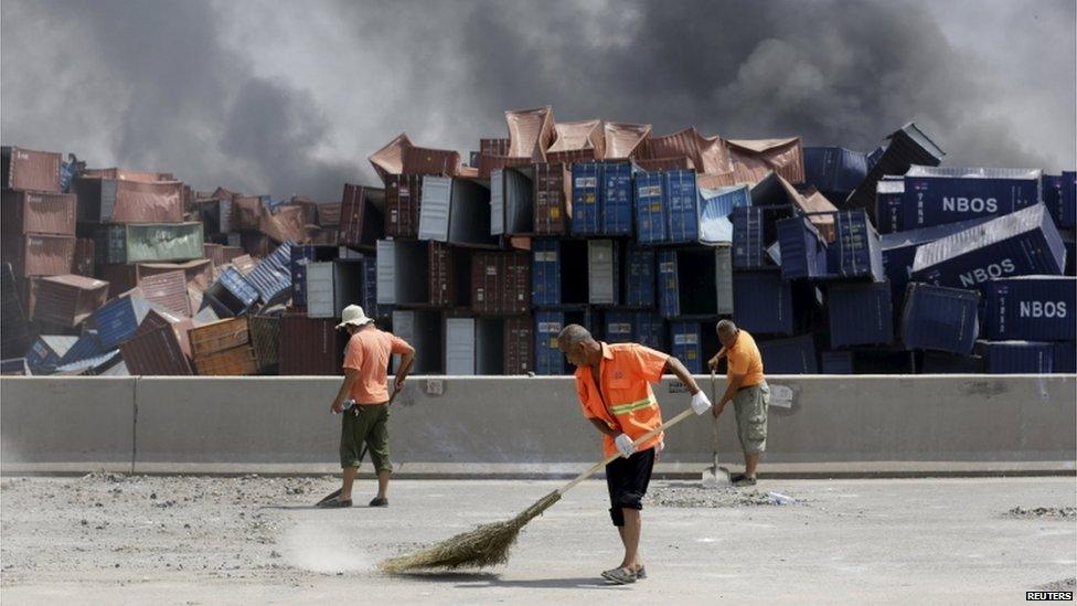 Workers clean a road near the site of the explosions at the Binhai new district, Tianjin, 13 August 2015