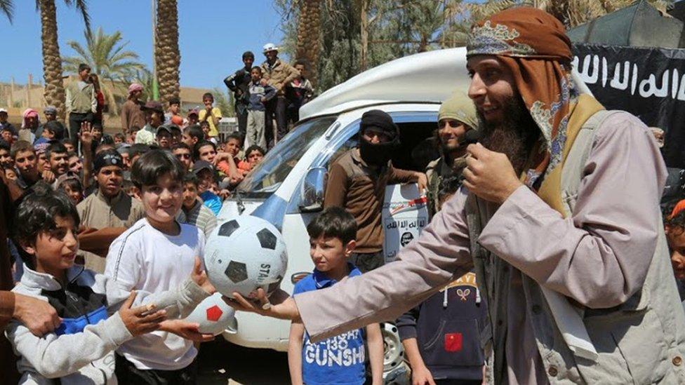 An Islamic State militant, right, gives a ball to a boy, left, during a street preaching event in Tel Abyad in Raqqa (14 January 2015)