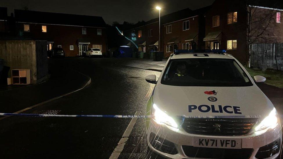 A police cordon and blue tent visible at the scene