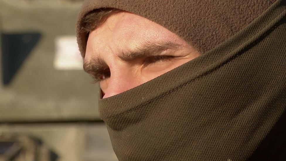 A man in army gear looks into the horizon