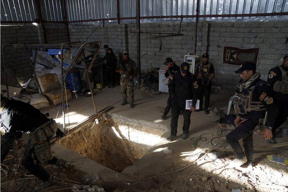 Iraqi security forces stand around a tunnel used by Islamic State militants at Bartila in the east of Mosul on October 20, 2016