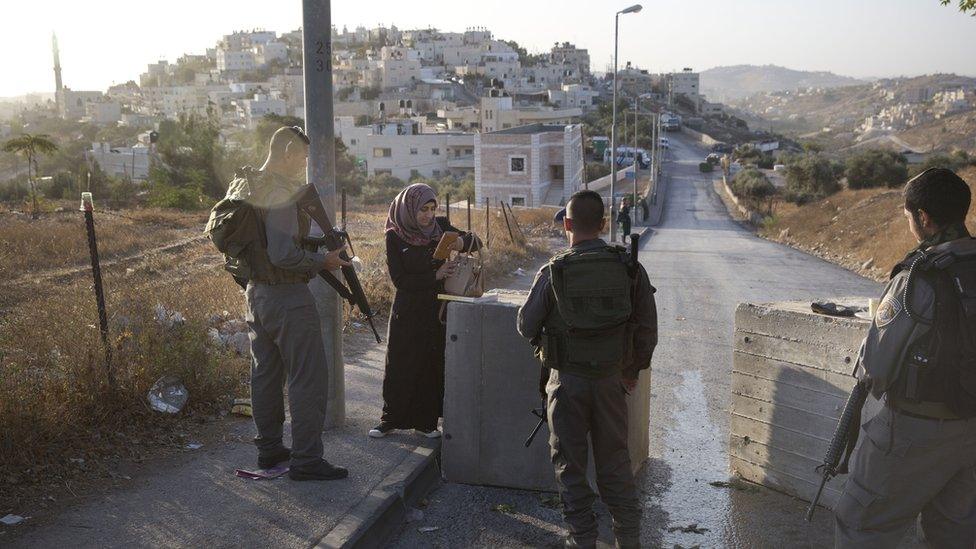 Israeli border police check a Palestinian woman's ID next to newly placed concrete blocks in East Jerusalem