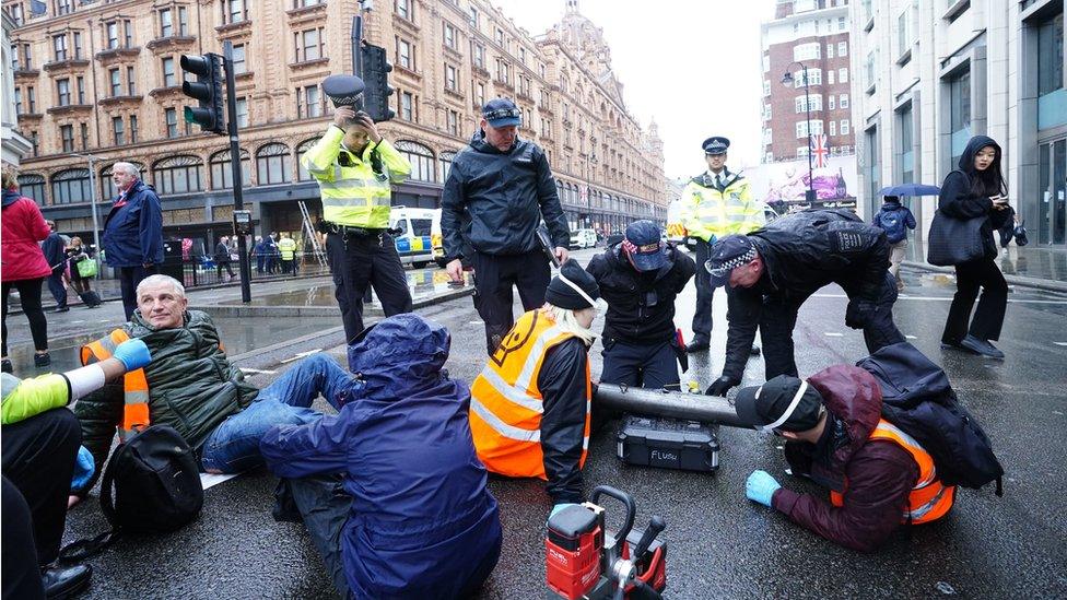 Police officers deal with activists from Just Stop Oil during their protest outside Harrods department store