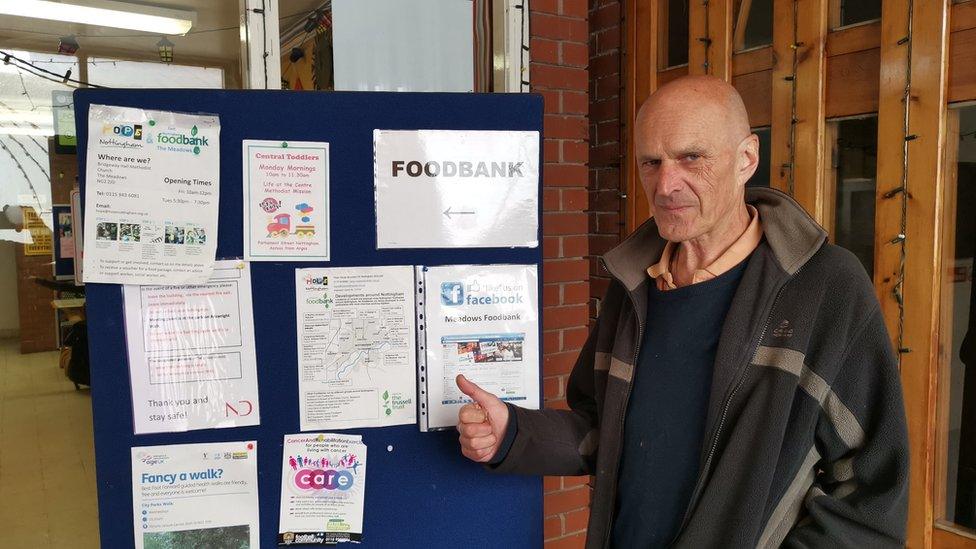 A man in front of a food bank sign