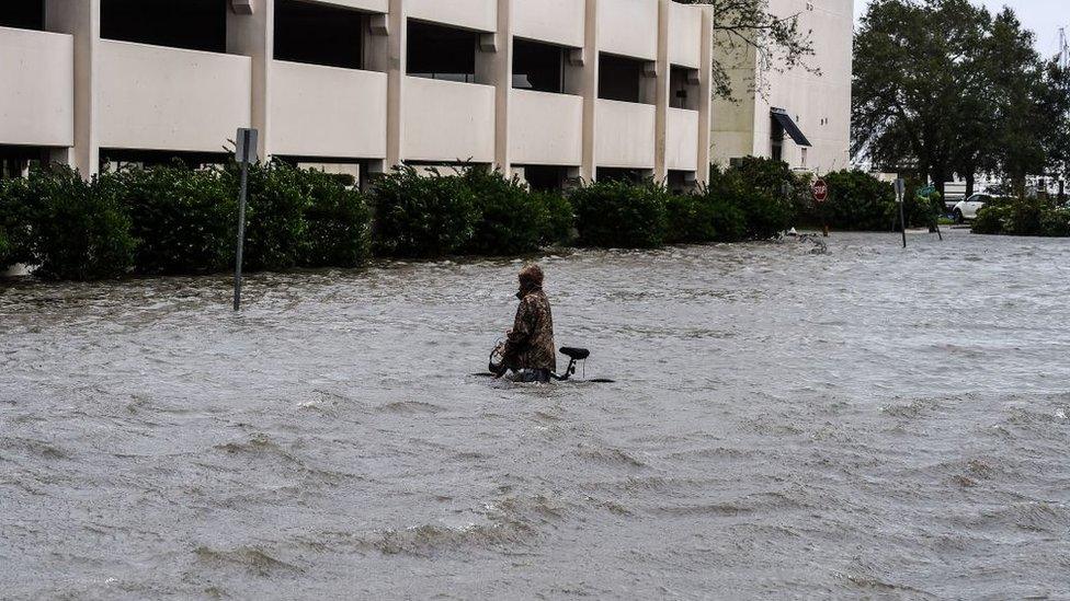 A man walks his bicycle through a street flooded by Hurricane Sally in Pensacola, Florida, on September 16, 2020