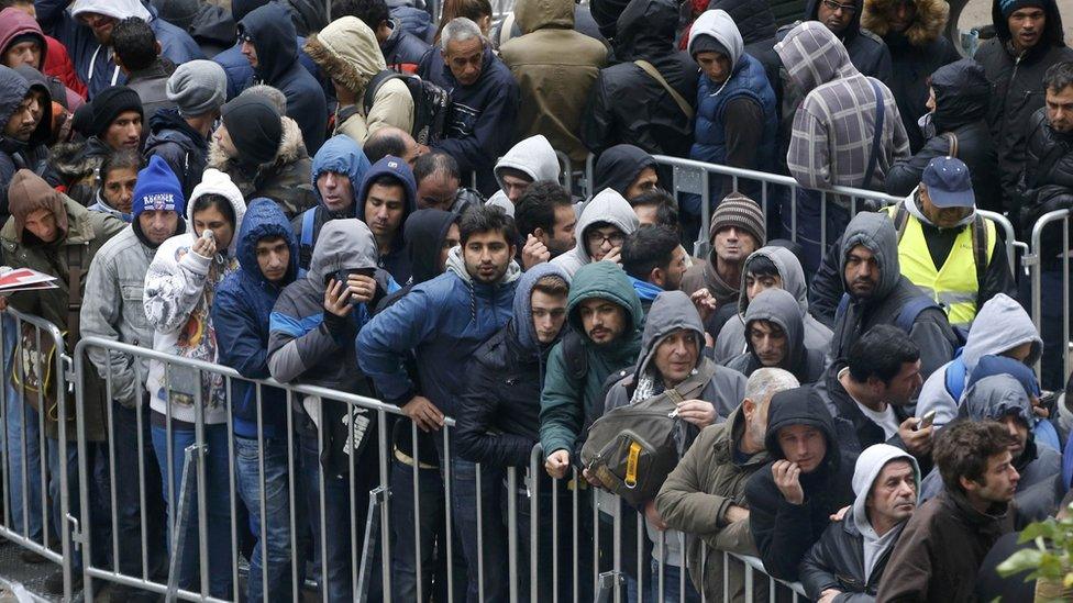 Migrants queue outside Office of Health and Social Affairs as they wait to register in Berlin