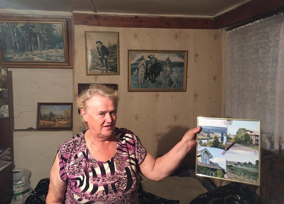 Russian woman in her guest house holding picture