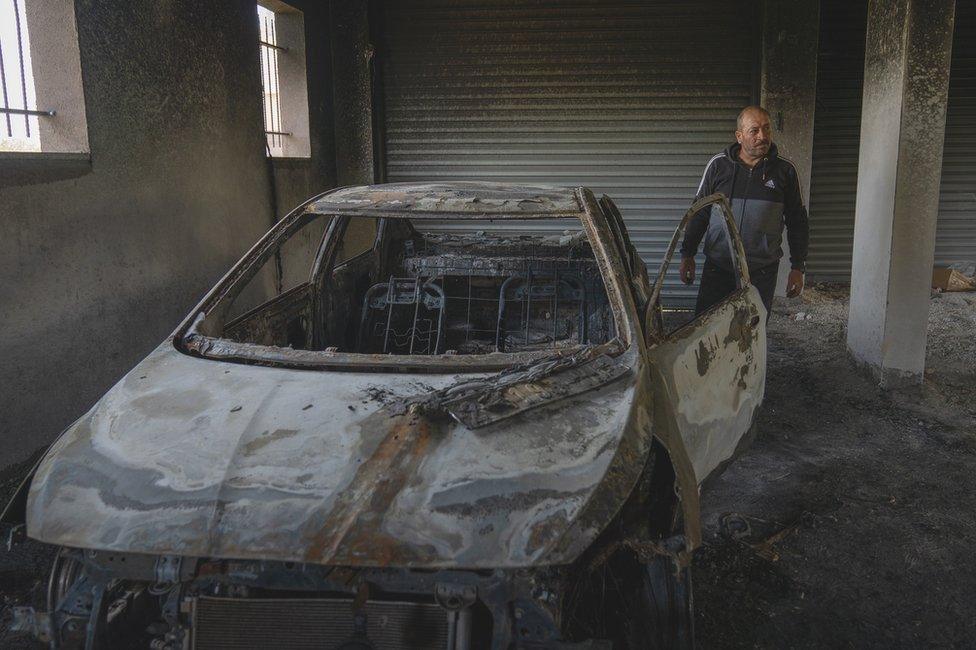 Dawbsheh in his burned garage, where both his cars he uses for his business were reduced to shells.