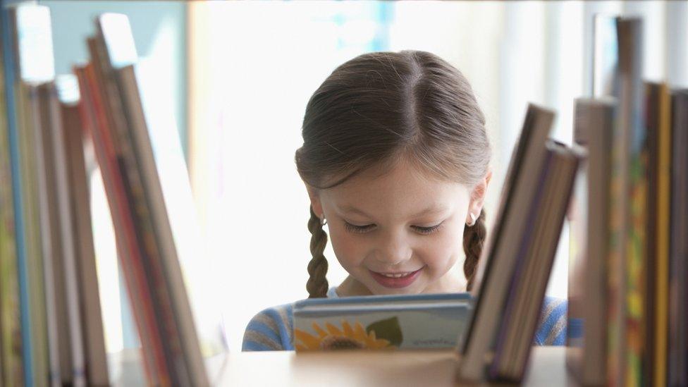 Girl reading a book from the shelf