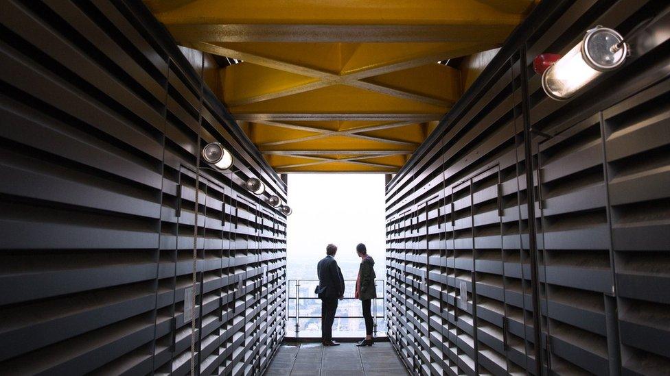 A couple look out at the London skyline from an upper floor of a newly constructed skyscraper, the Leadenhall Building