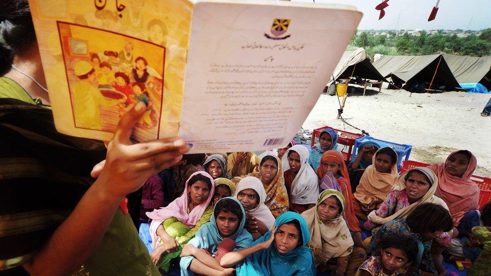 Pakistani girls listen to a teacher at a makeshift tent school