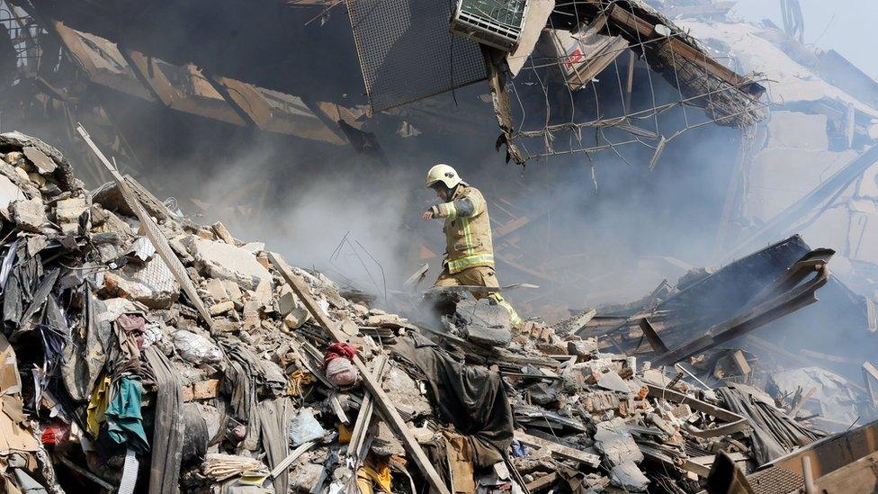 A firefighter stands in the rubble of the collapsed Plasco building in Tehran, Iran (19 January 2017)