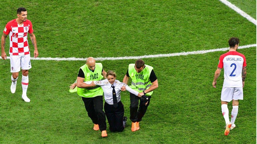 A member of the Russian protest-art group Pussy Riot, is escorted by stewards during the Russia 2018 World Cup final football match