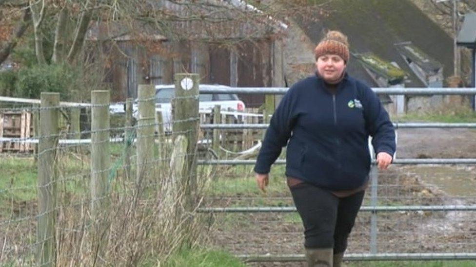 Florence Mannerings walks through a farm gate surrounded by muddy fields with her dog ahead of her