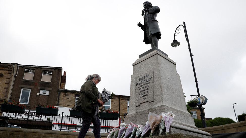 Woman lays flowers by statue