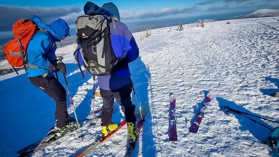 Chris and another person on skis atop a mountain