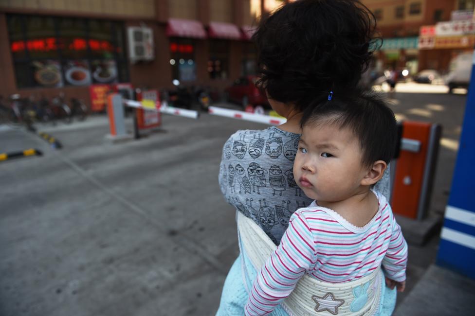 This photo taken on June 24, 2015 shows a woman carrying a baby in Yanji, in China's northeast Jilin province