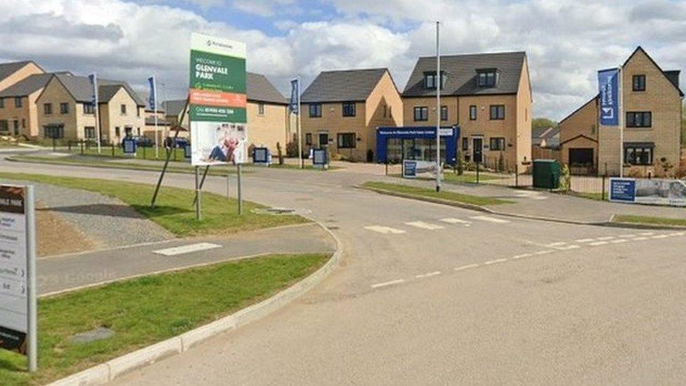 Entrance to new housing estate with marketing boards