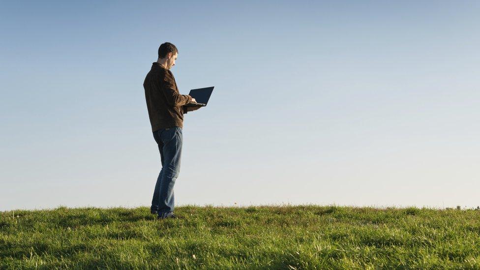 Man using laptop in a field