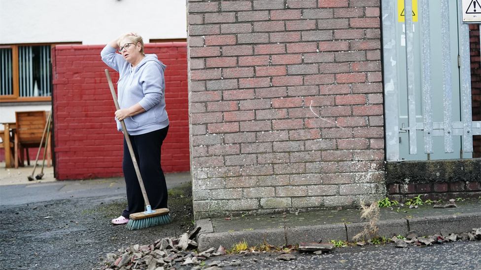 woman sweeps up debris from explosion