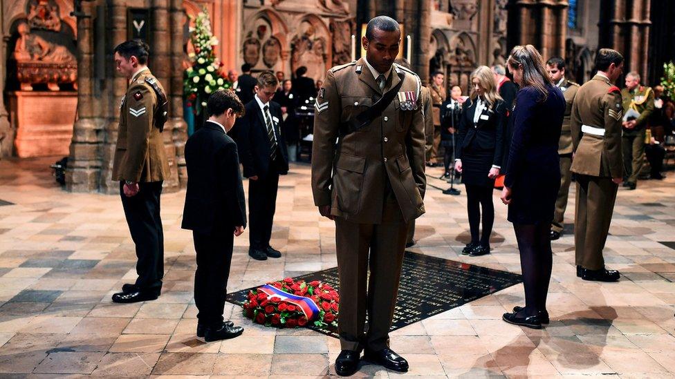 Civilians and military personnel standing in silence next to the Tomb of the Unknown Warrior in Westminster