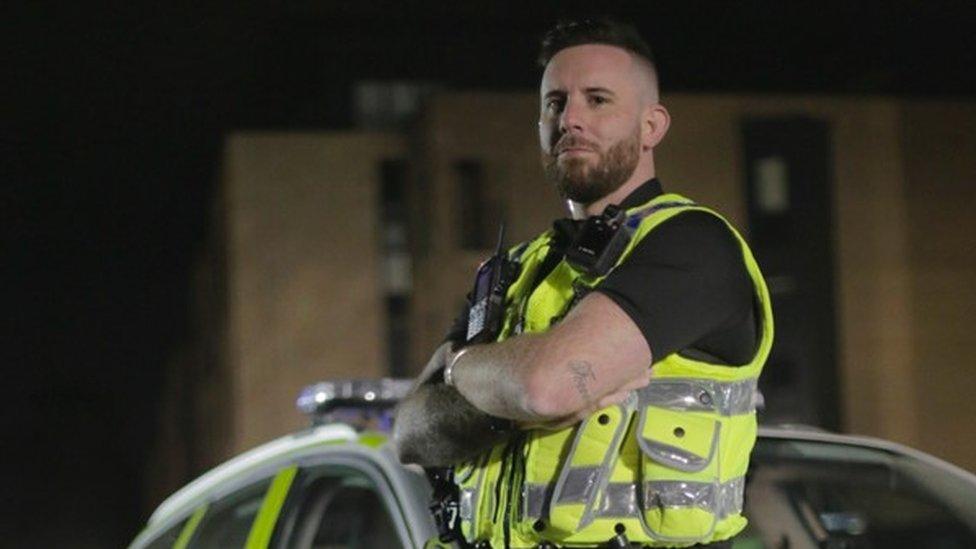 Mr Williamson standing in front of a police car in hi-vis jacket