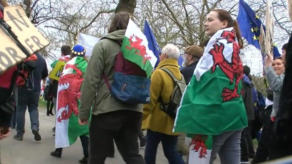 People wearing a Wales flag at march