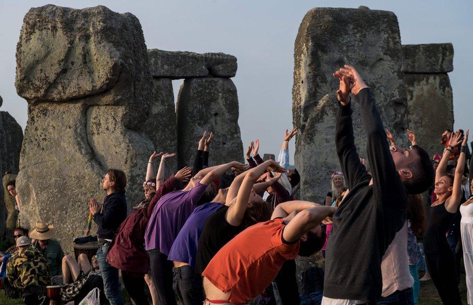 Revellers practice yoga as the sun rises during the pagan festival of Summer Solstice at Stonehenge in Wiltshire, southern England on June 21, 2017