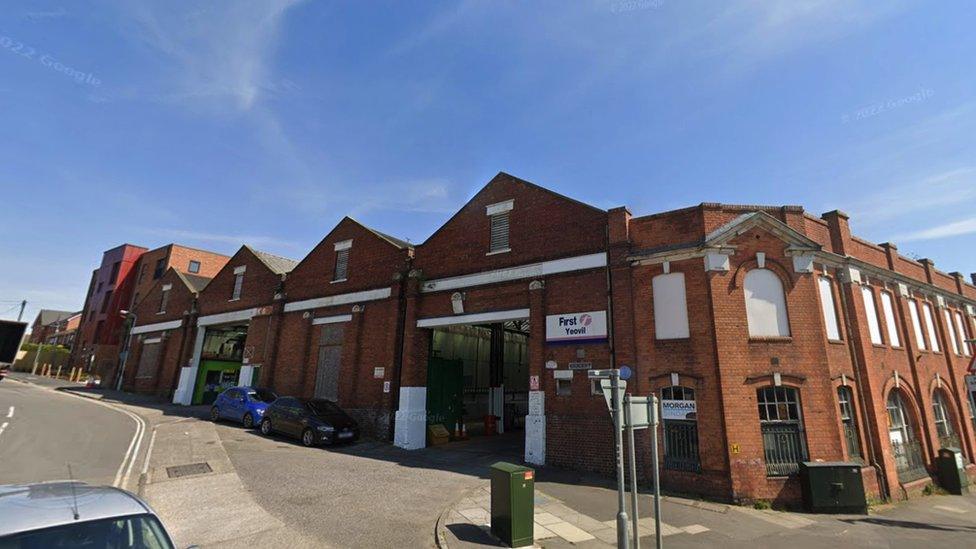 Google Maps view of First Bus depot in Reckleford, Yeovil. It is a large, red brick building with a white sign featuring the pink and blue First Bus Yeovil sign.