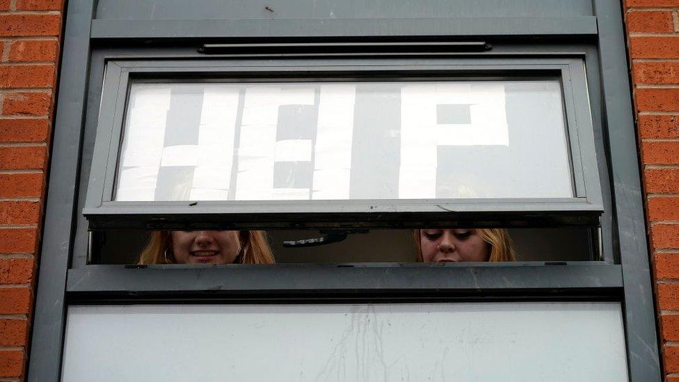 Isolating students peer out of their accommodation window in Manchester