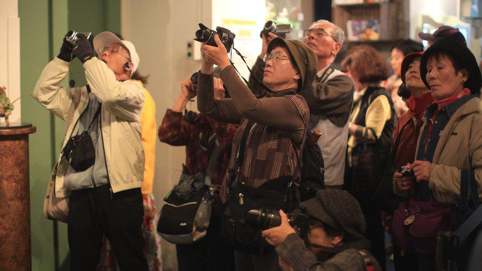 Japanese tourists take holiday photographs at The World of Beatrix Potter attraction in Windermere, United Kingdom.