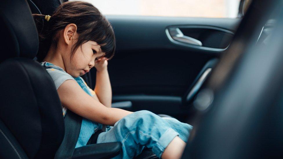 Child waiting in car in traffic