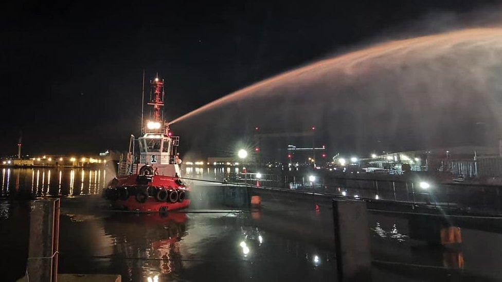 A fire-fighting tug boat spraying the fire with water