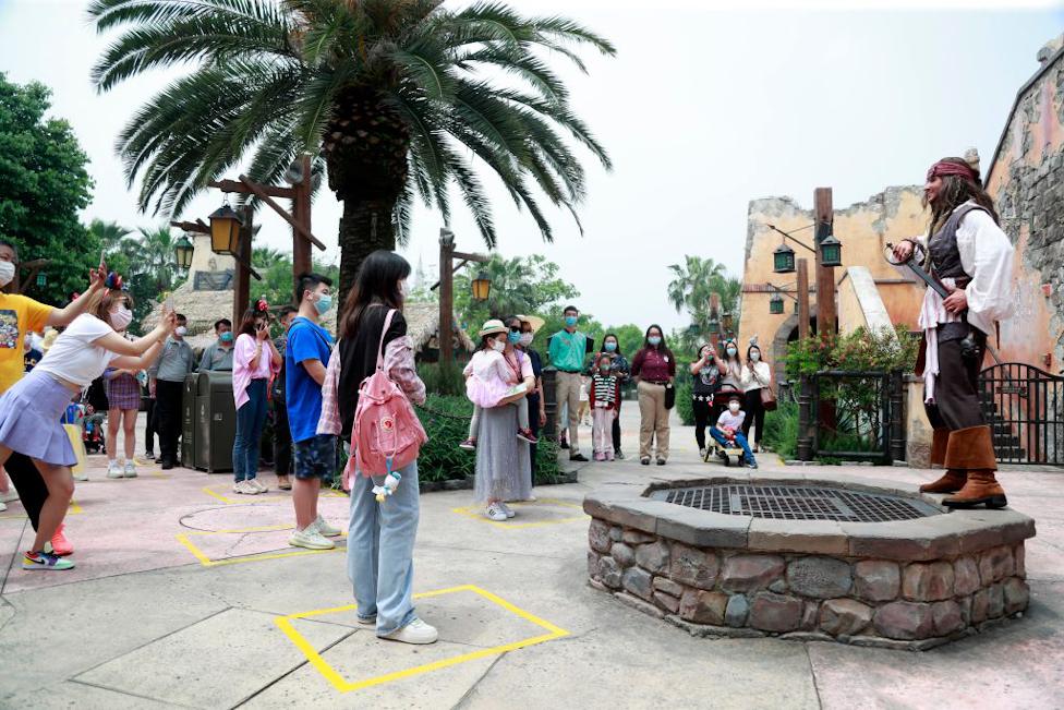 Visitors wearing face look at a performer dressed as Captain Jack Sparrow