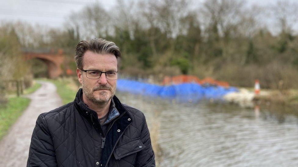 Councillor Chris Watts looks into the camera standing on the canal towpath