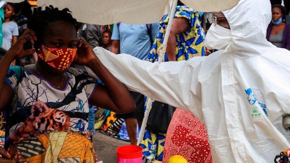 A street shop-keeper is receiving a face mask, as a preventive measure against the spread of the COVID-19 coronavirus, from a Filimbi activist in the very popular district of Selembao, during a COVID-19 coronavirus awareness campaign led by Filimbi and Lucha movements in Kinshasa on May 29, 2020