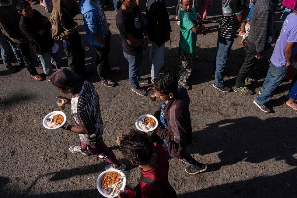 A group of Central American migrants are seen lining up for food outside a temporary shelter at the US-Mexico border in Tijuana, Baja California state, Mexico, on 23 November