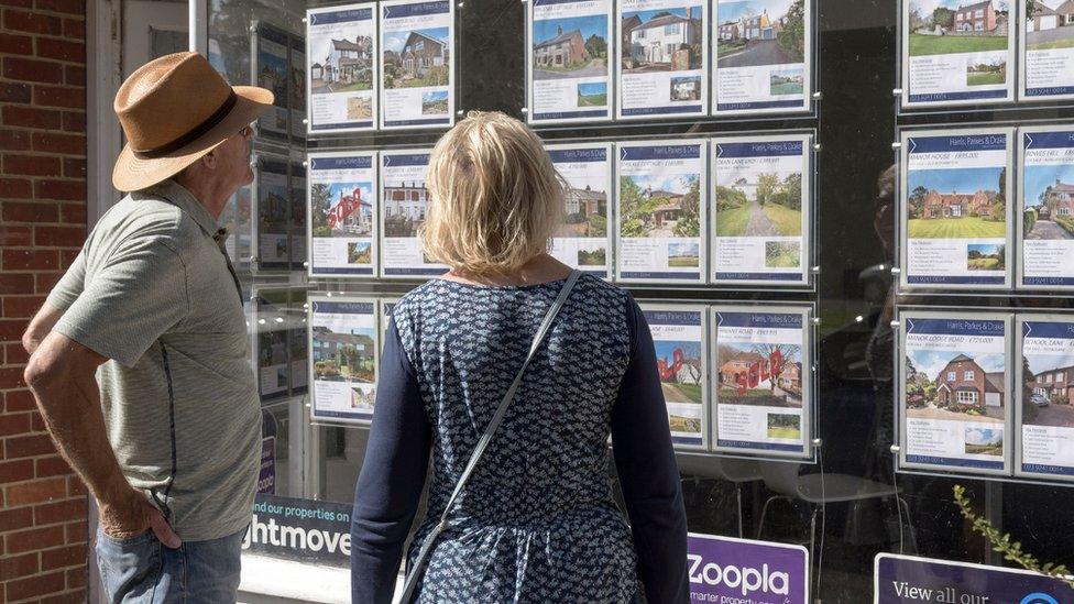 People looking in an estate agent's window