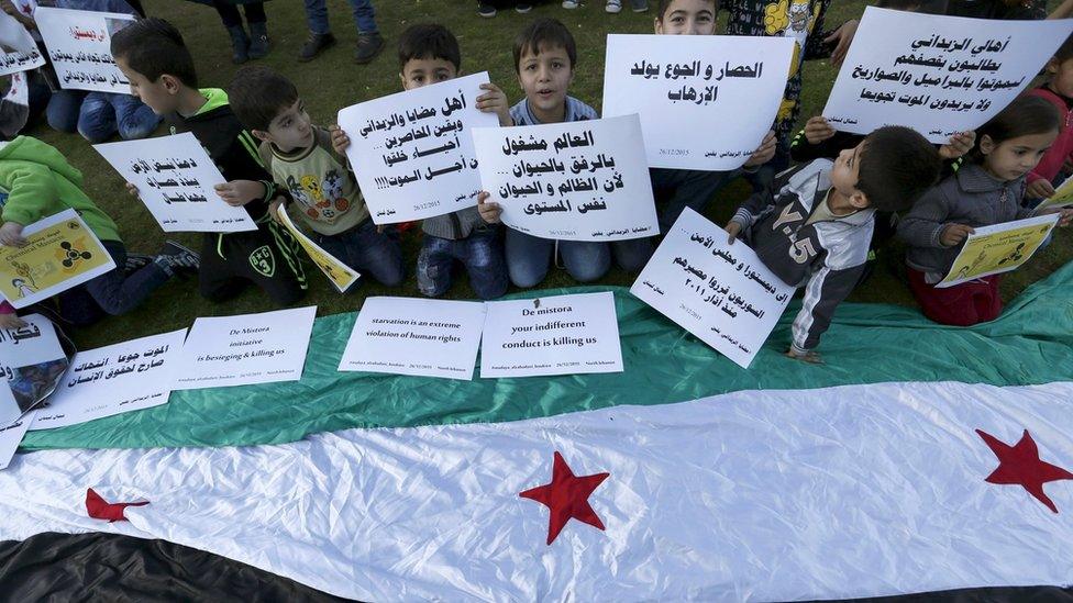 Syrian children carry placards as they call for the lifting of the siege off Madaya in Syria, in front of the offices of the UN headquarters in Beirut, Lebanon (26 December 2015)