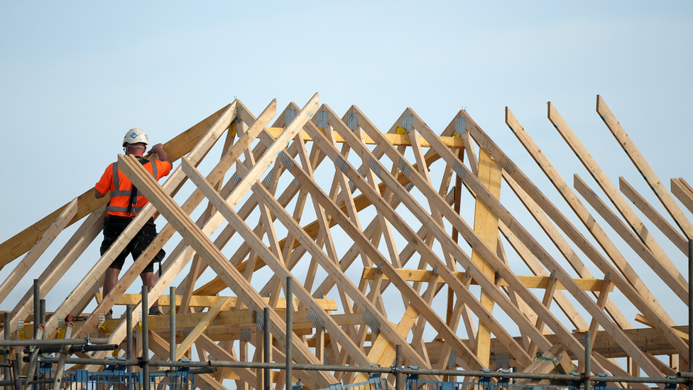 Man building a roof on a new house