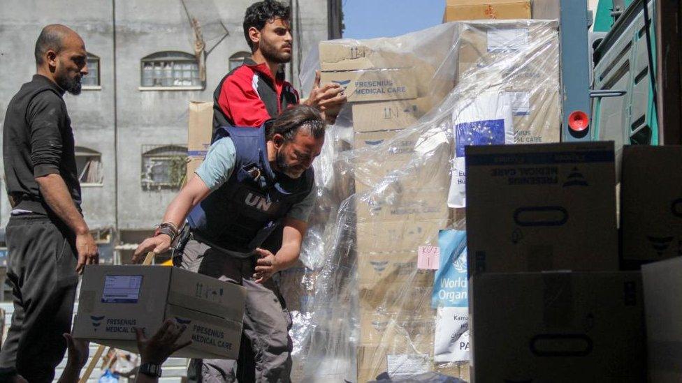 People unload medical aid from a truck, near Kamal Adwan Hospital in the northern Gaza Strip, amid the ongoing conflict between Israel and Hamas